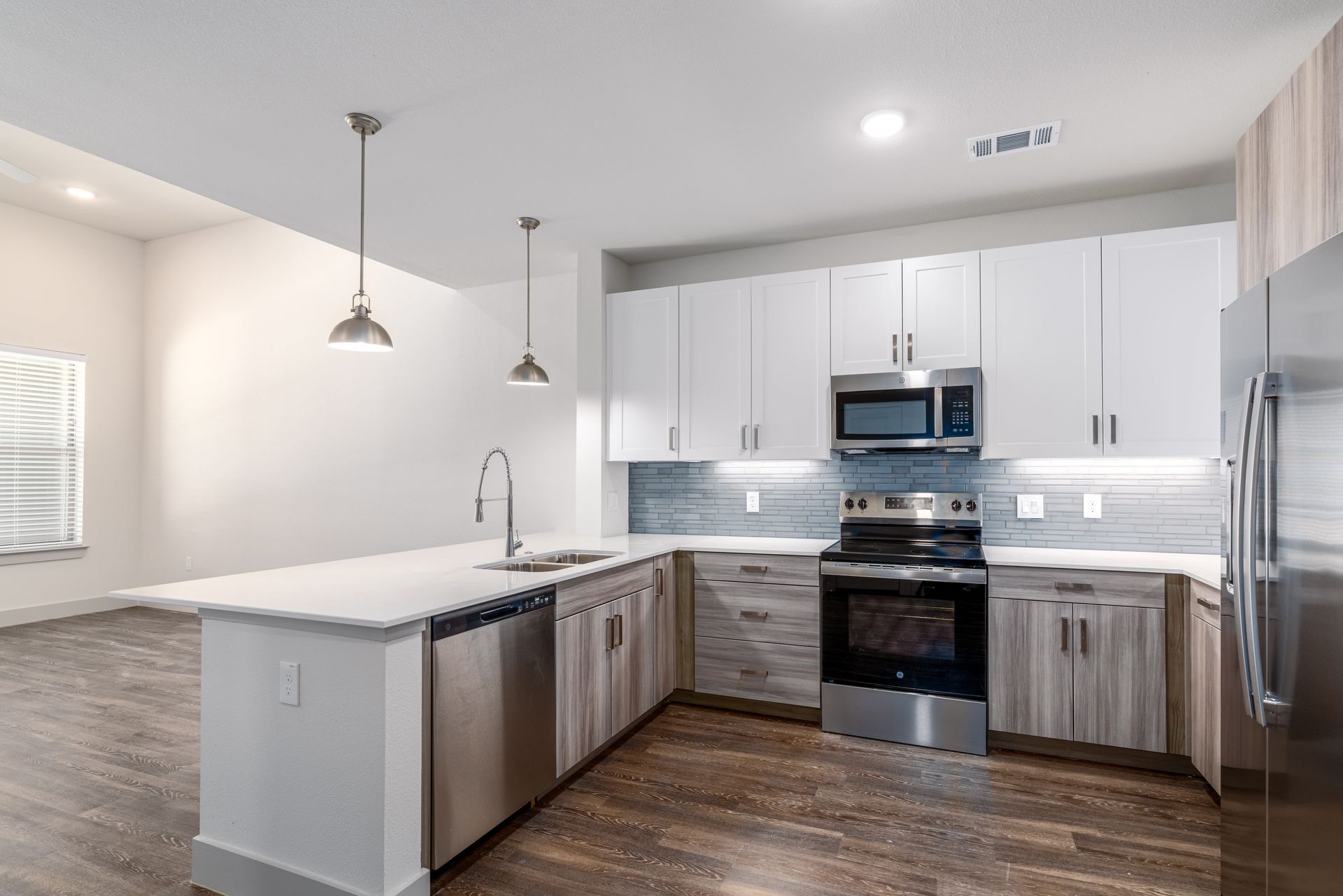 Bright modern kitchen with white cabinets, stainless steel appliances, island, and wood flooring