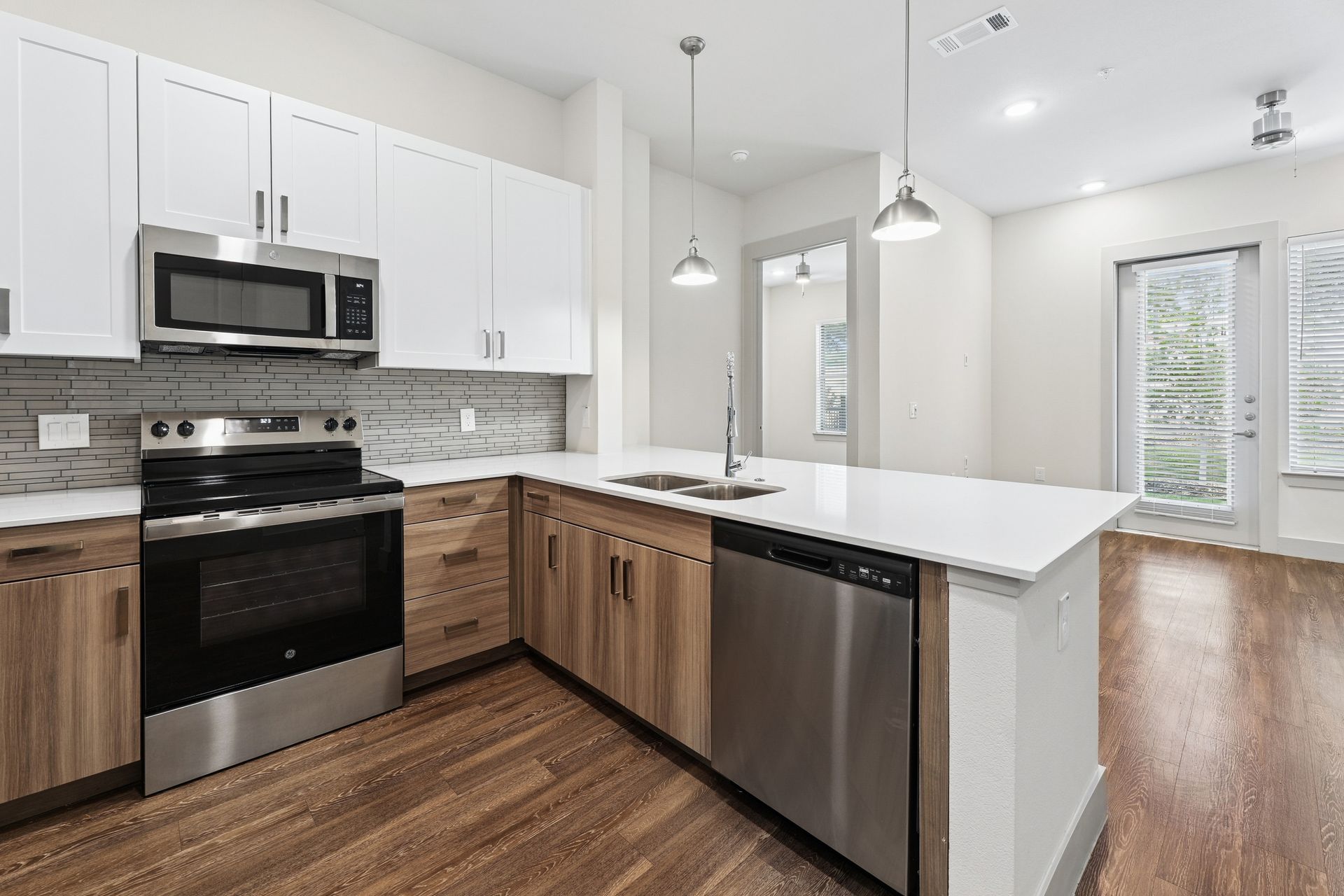 Modern kitchen with white cabinets, black appliances, wood floors, and a large white island