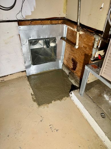 A basement wall opening with a metal duct, covered in new concrete.