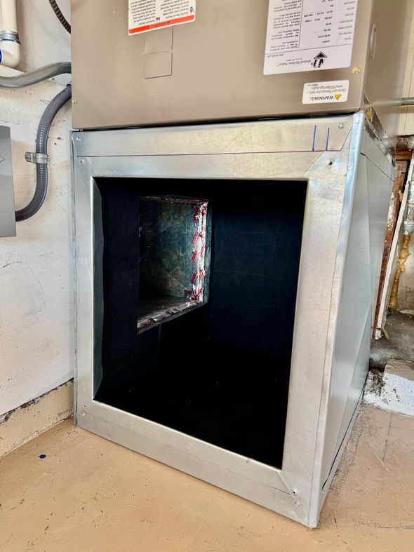Silver HVAC unit with open filter compartment, black filter, concrete floor.