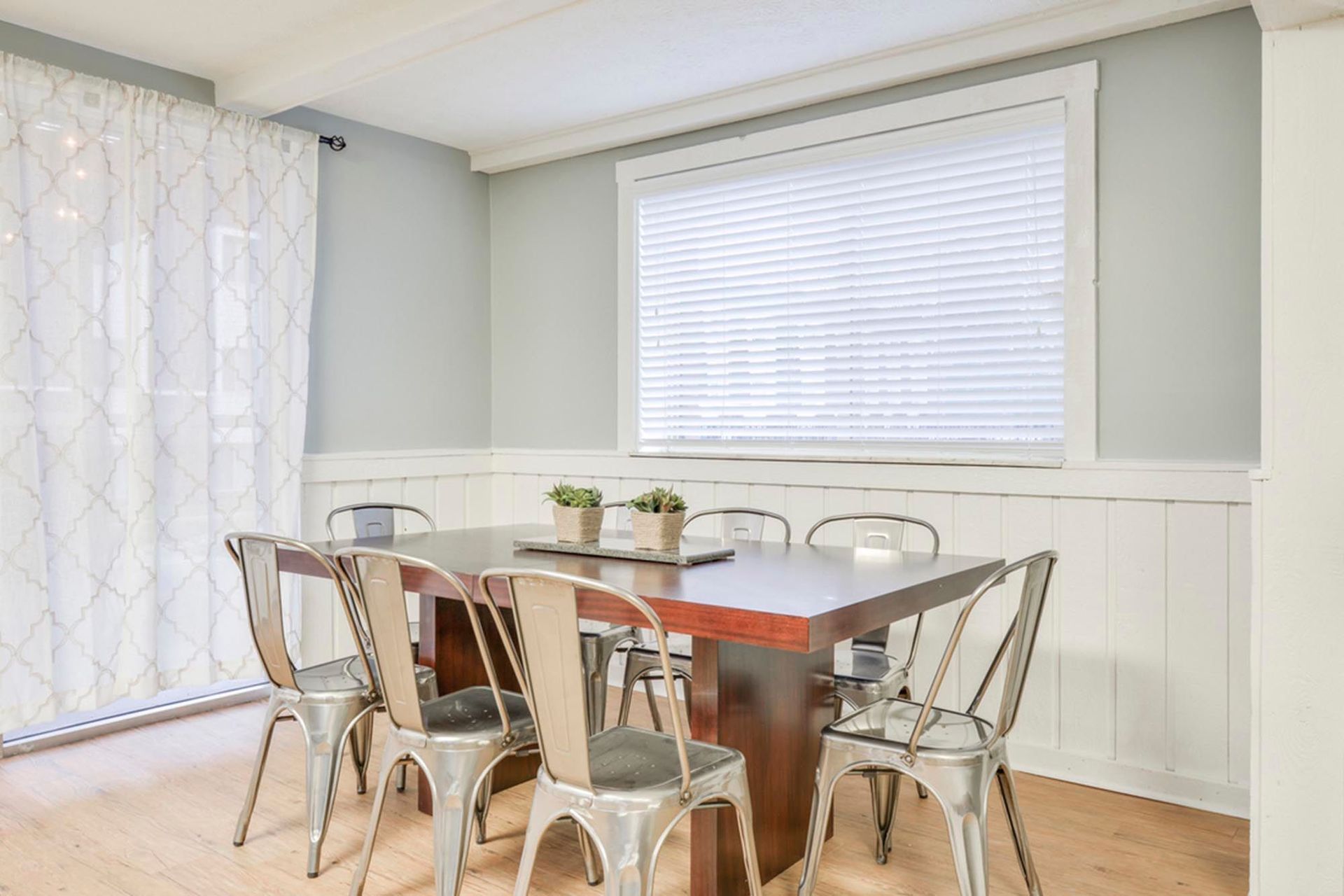 clubhouse dining area with a wooden table, metal chairs, light blue walls, and a window with blinds at the Reserves at Arlington in Columbus, OH.