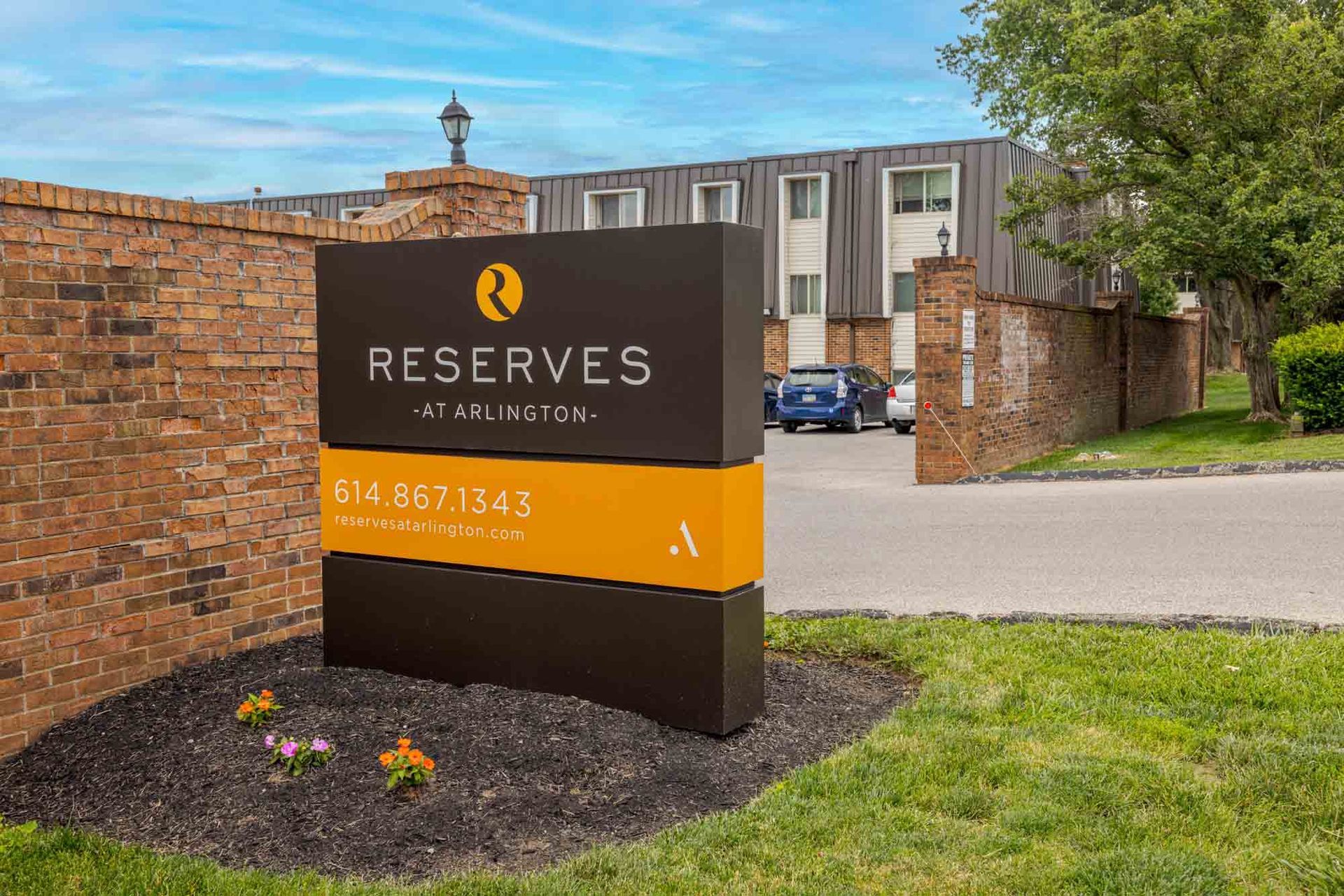 Reserves apartment community sign in front of brick buildings and a parking lot