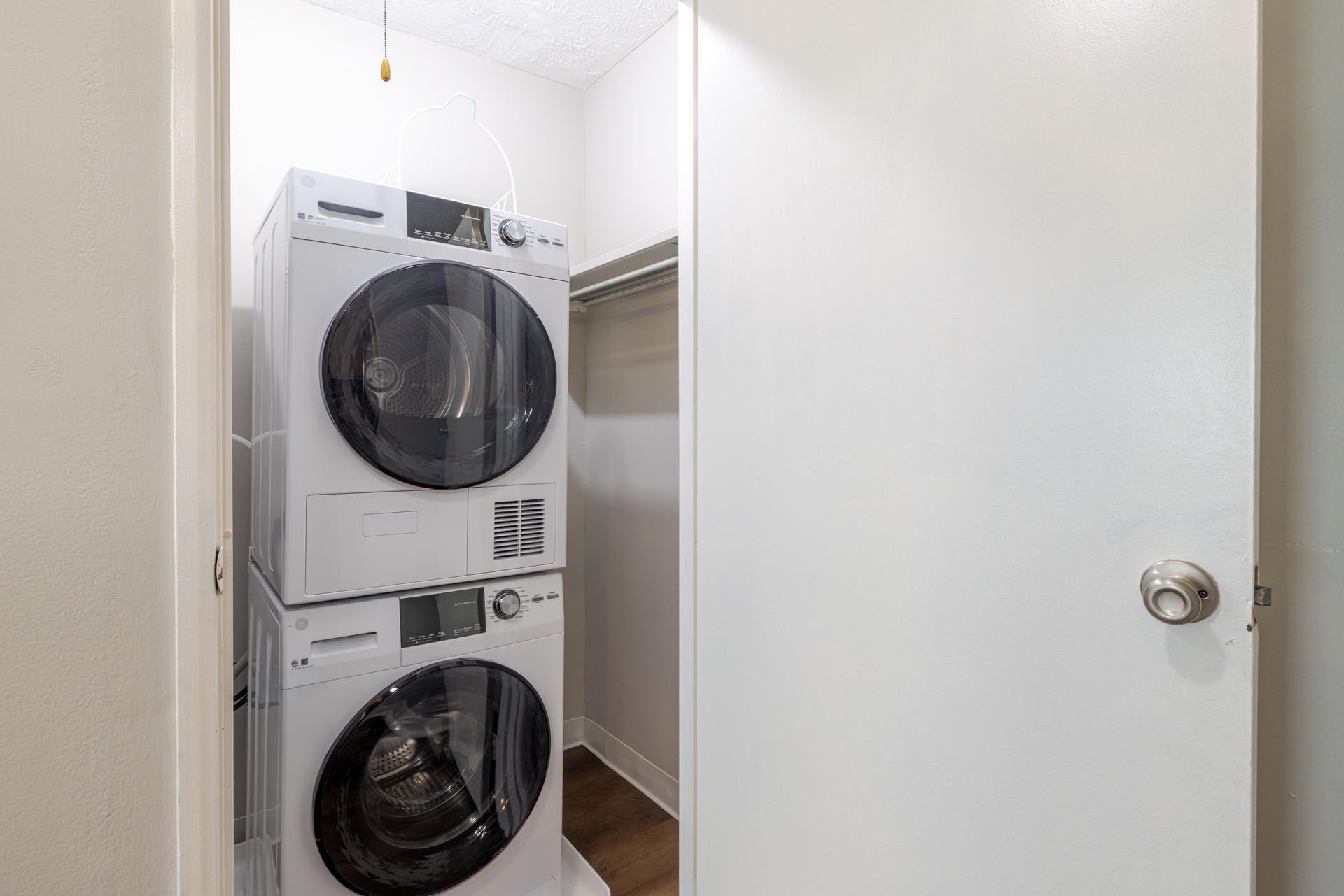 Stacked washer and dryer in a narrow laundry closet with a partially open door at the Reserves at Arlington in Columbus, OH.