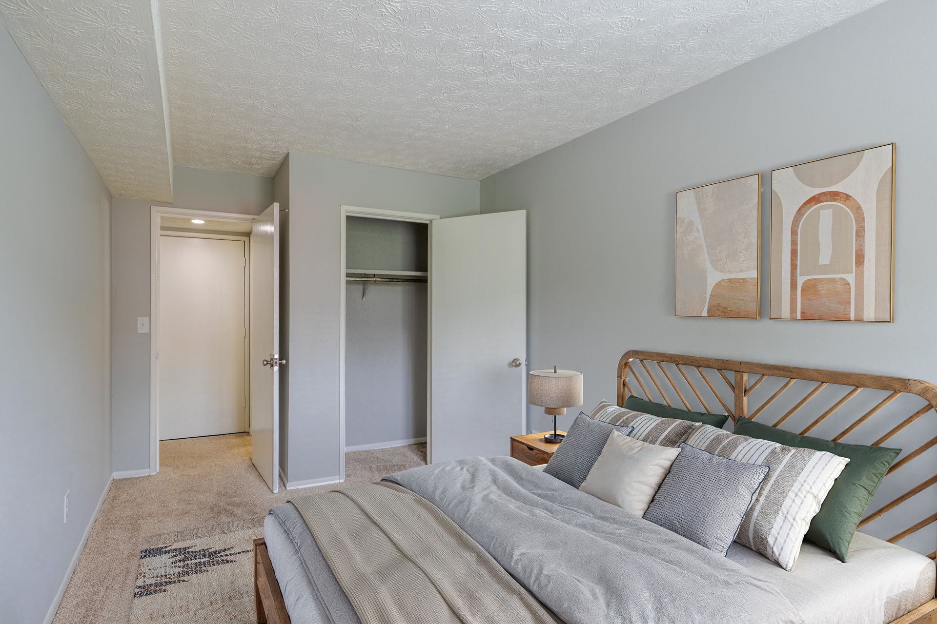 Bright bedroom with gray walls, bed, open closet, and hallway view at the Reserves at Arlington in Columbus, OH.