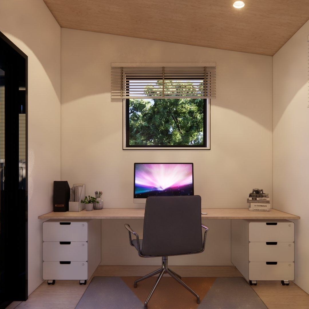 A computer is on a desk in a room with a window