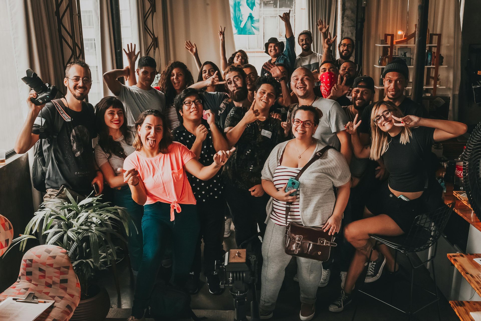 Group of diverse people smiling, celebrating inside a bright, decorated room.