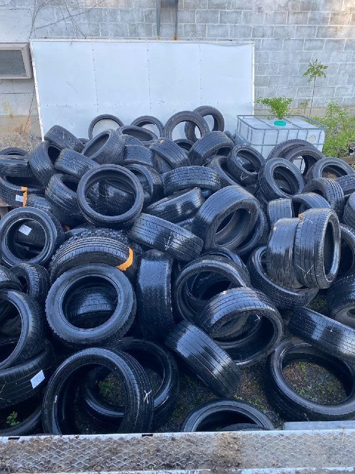 Pile of black tires outdoors, likely for recycling or disposal.