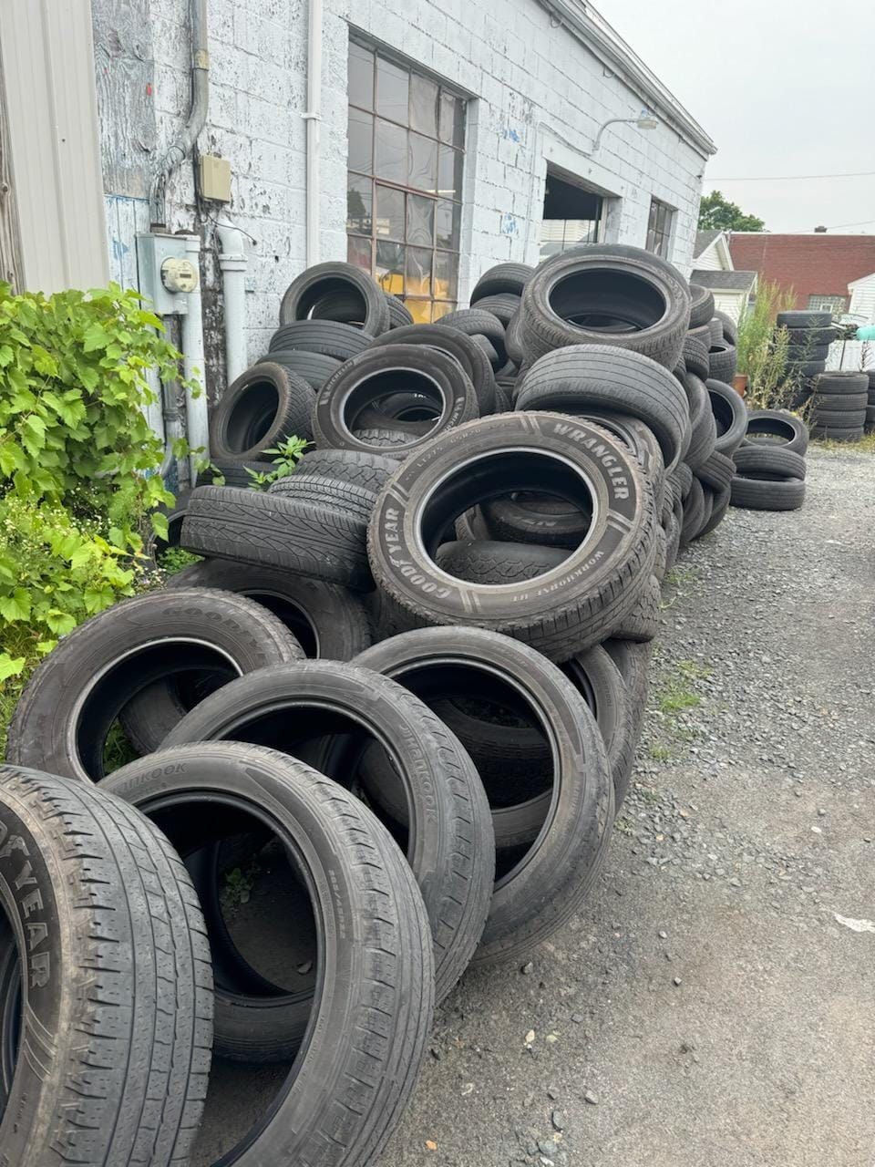 Pile of used car tires stacked outside a building.