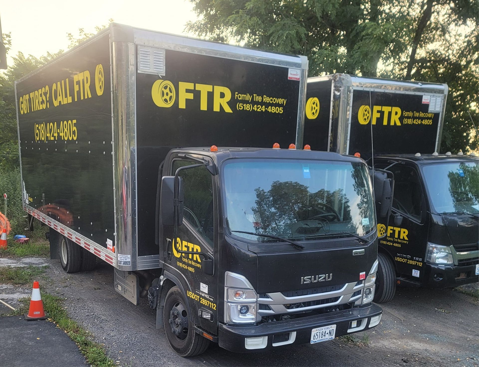 Three black Isuzu box trucks parked outdoors; company name FTR on the sides.
