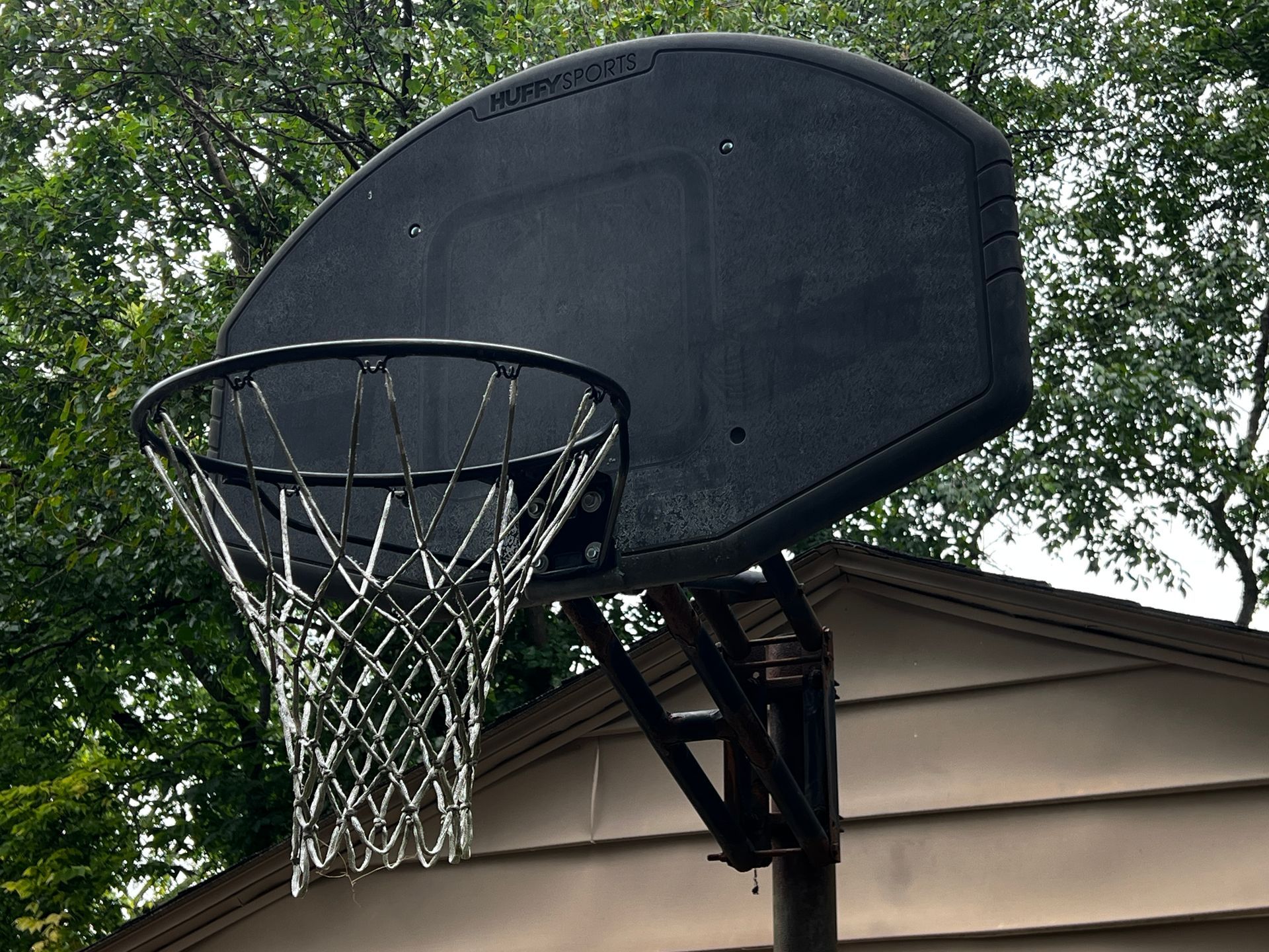 Broken basketball hoop with a torn net on an outdoor backboard.