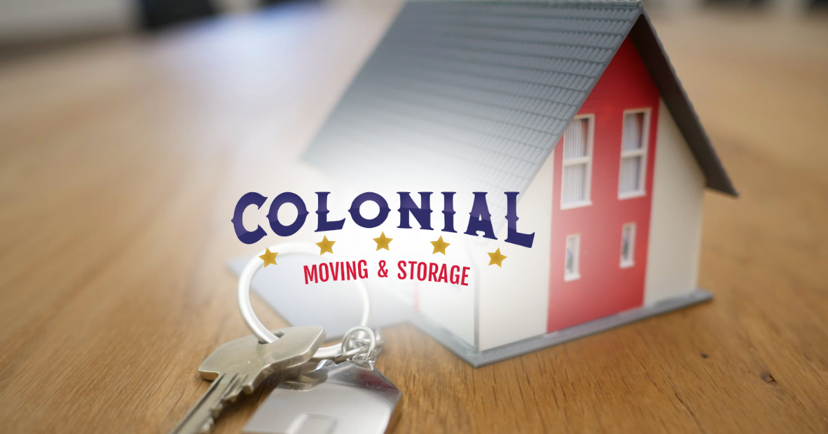 Colonial Home & Storage logo beside a red house model with keys on a wooden table