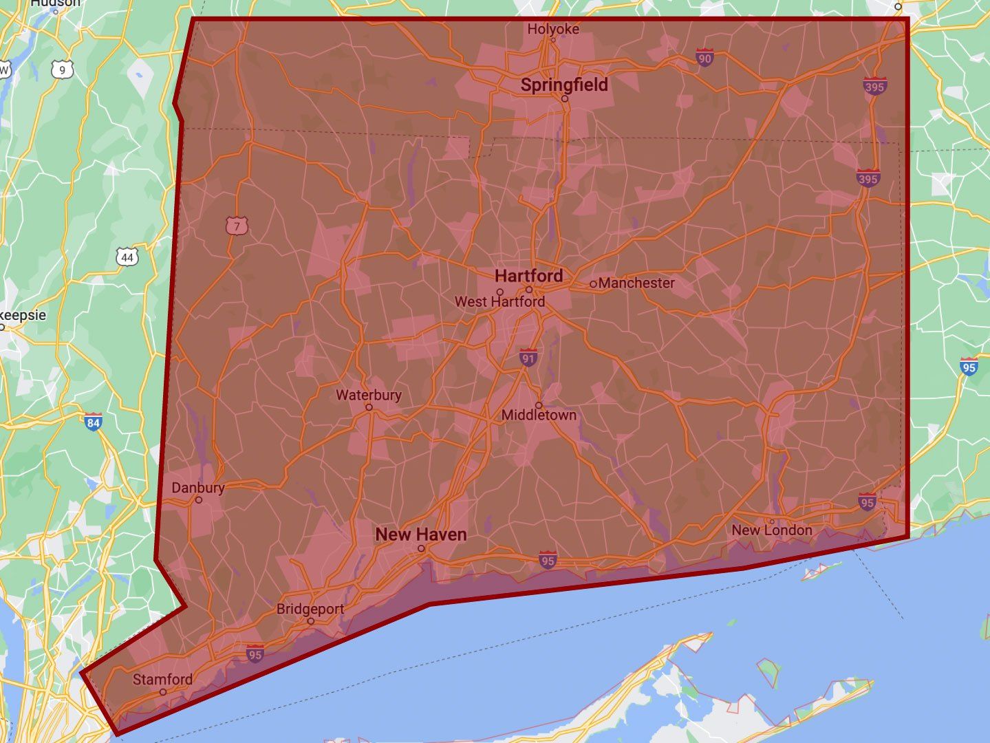 Red outlined region map over a coastal area, with a pink-tinted highlighted zone spanning roads and towns.