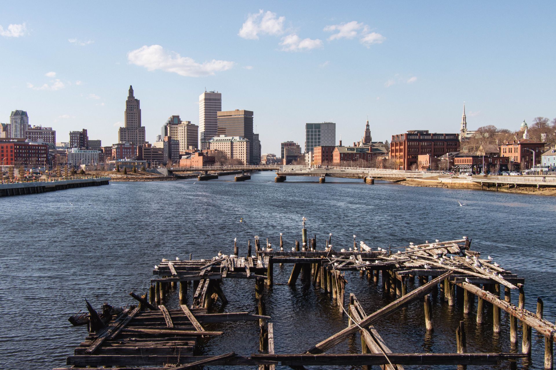 City skyline across a river with icy water and a wooden dock in the foreground under a clear sky