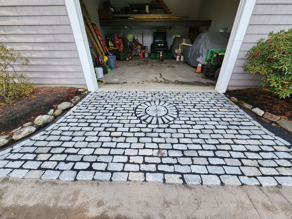 Cobblestone driveway leading to an open garage with tools and storage inside
