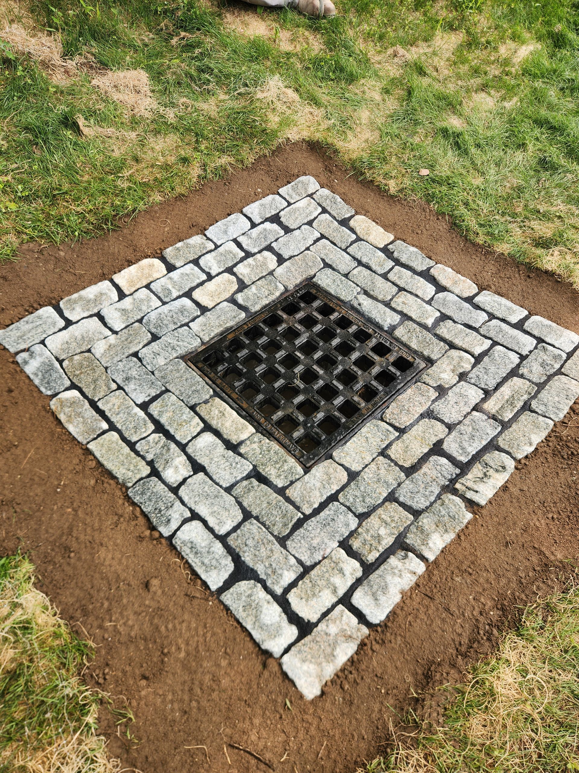 Blue-and-white striped pipe protruding from a dirt trench in a rocky area
