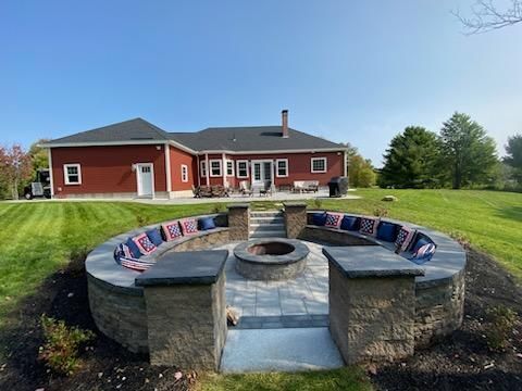 Aerial view of a house with a circular driveway, trees, and a small pond in the yard.