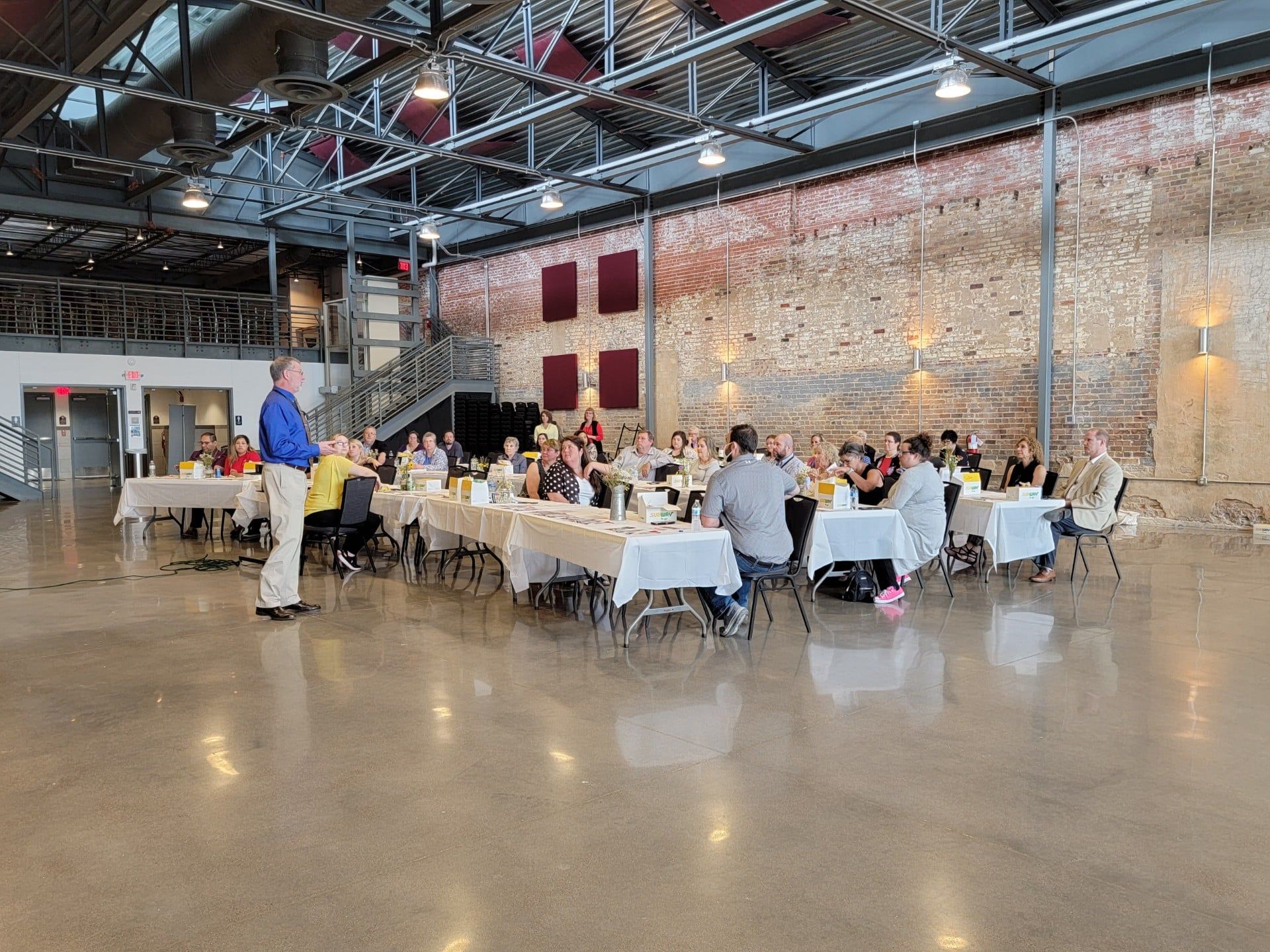 A group of people are sitting at tables in a large room.