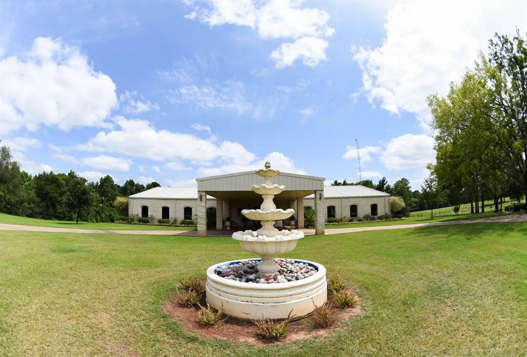A large white house with a fountain in front of it.