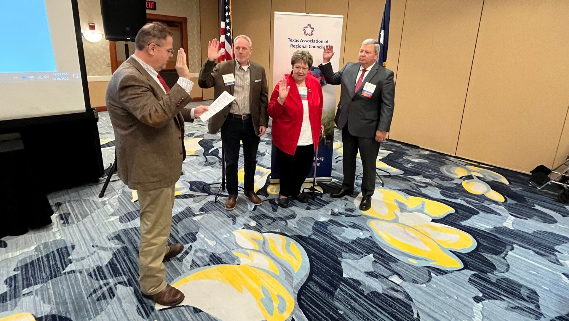 A group of people are standing in a room taking oaths.