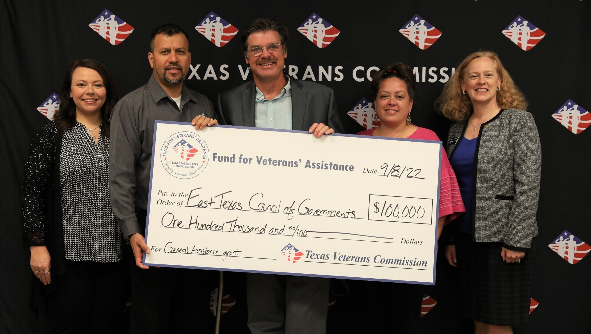 A group of people holding a large check that says texas veterans