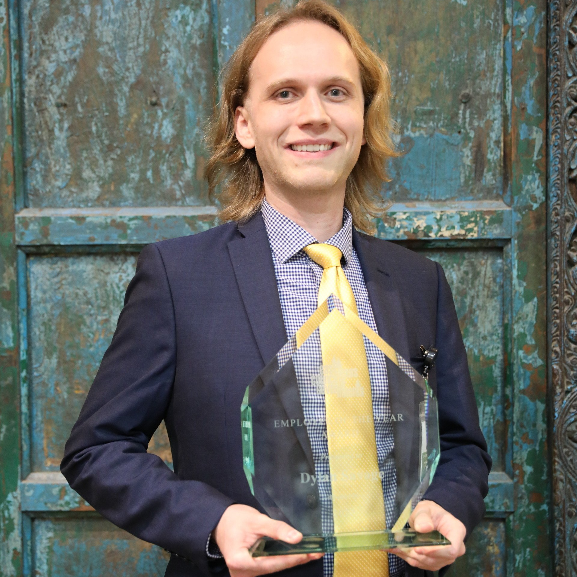 A man in a suit and tie is holding a trophy