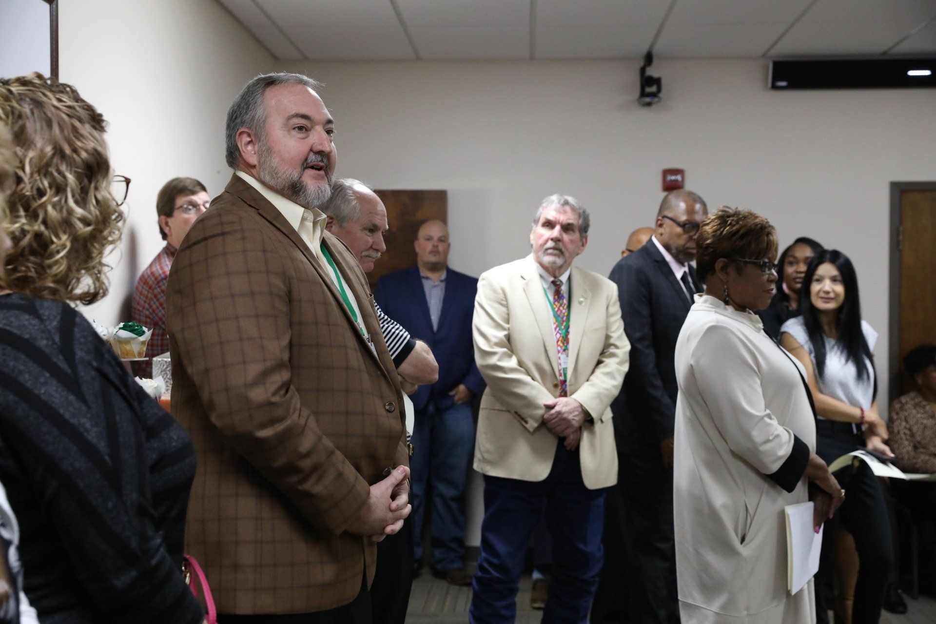 A man is standing in front of a group of people in a room.