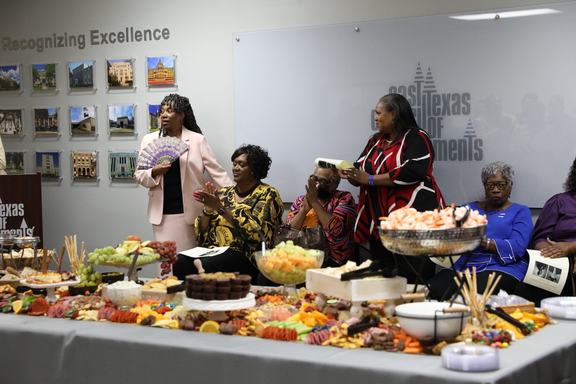 A group of women are sitting around a table filled with food.