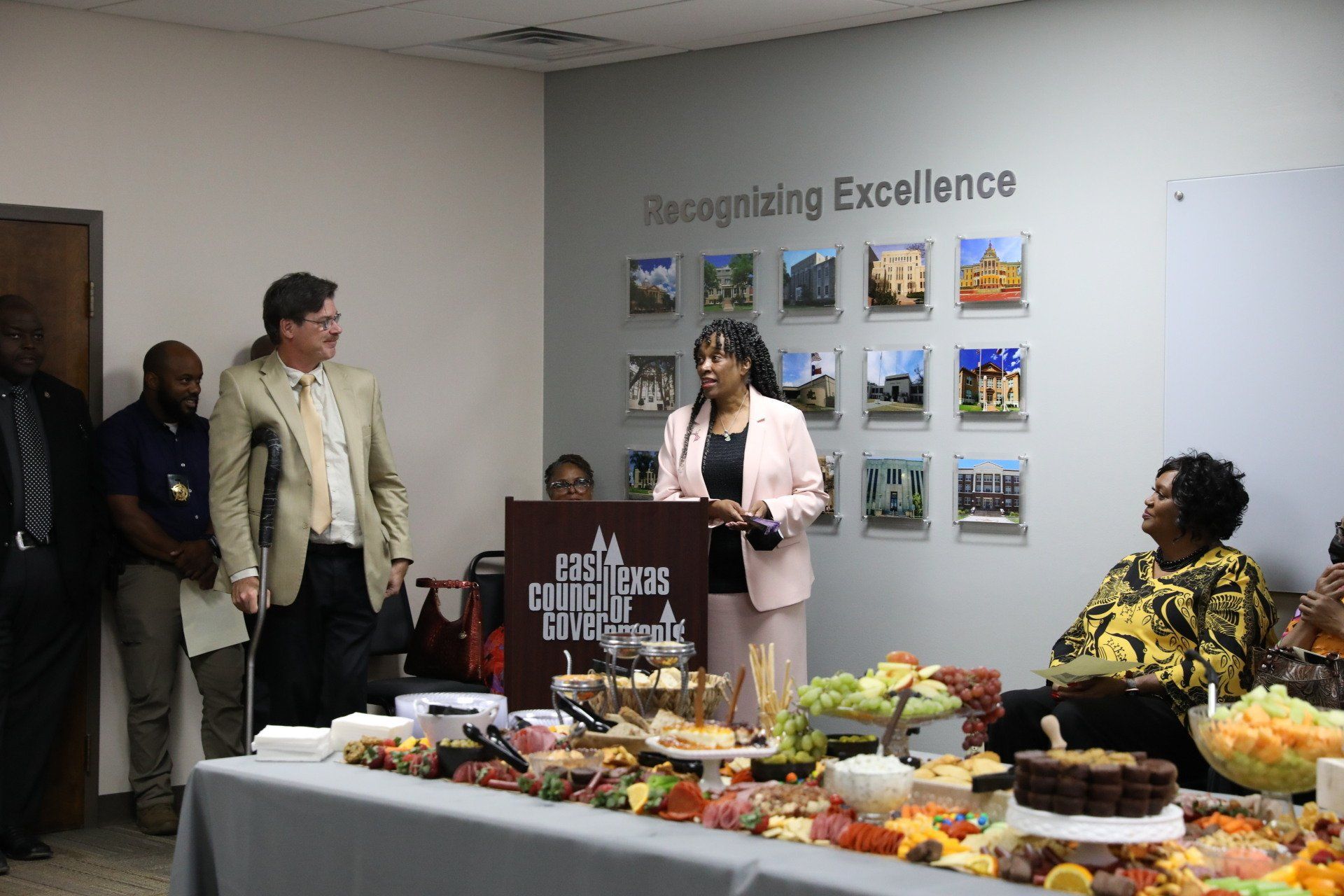 A woman is standing at a podium talking to a group of people.