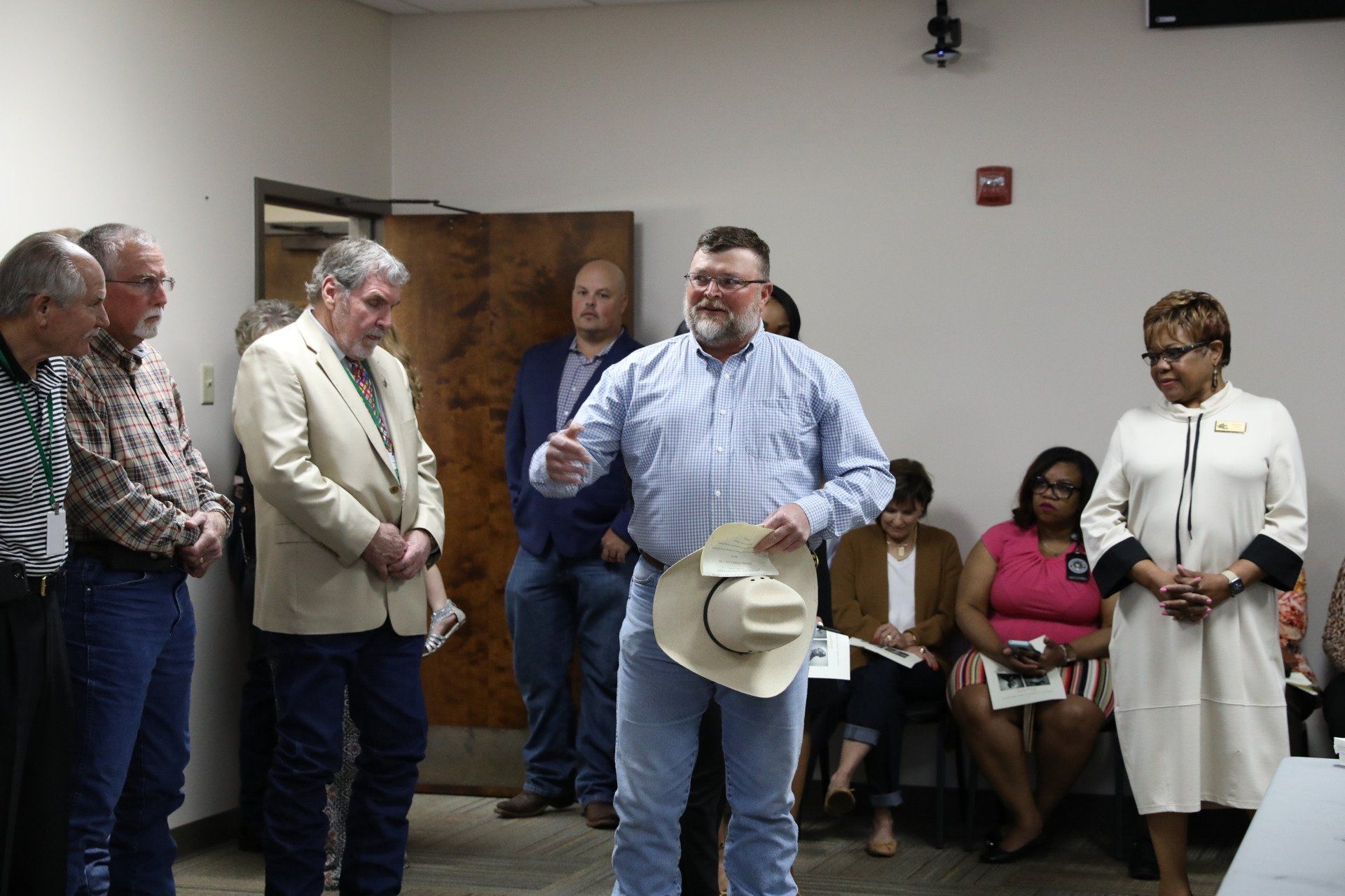A man wearing a cowboy hat is standing in front of a group of people.