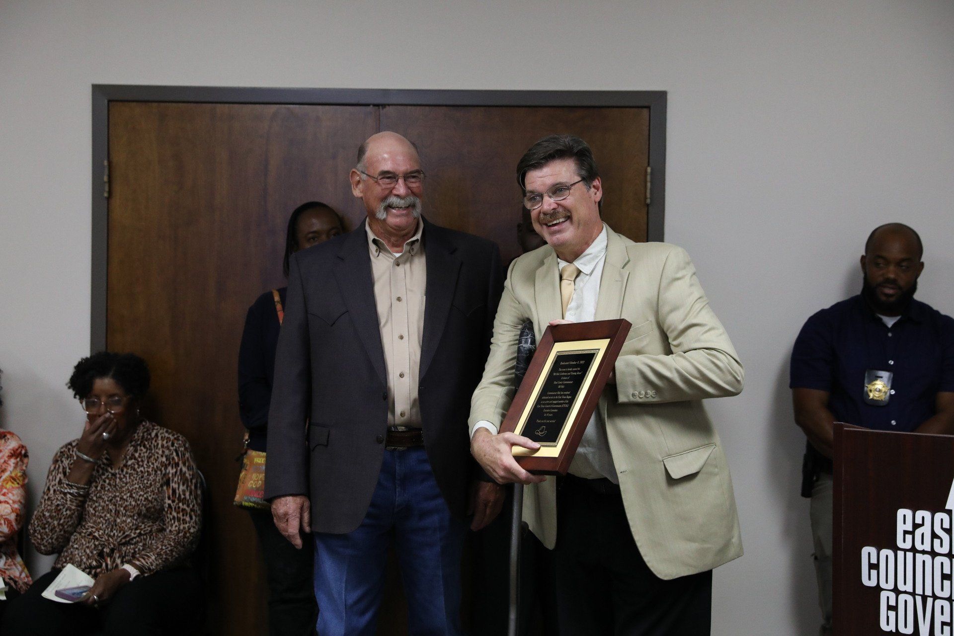 Two men are standing next to each other holding a plaque.