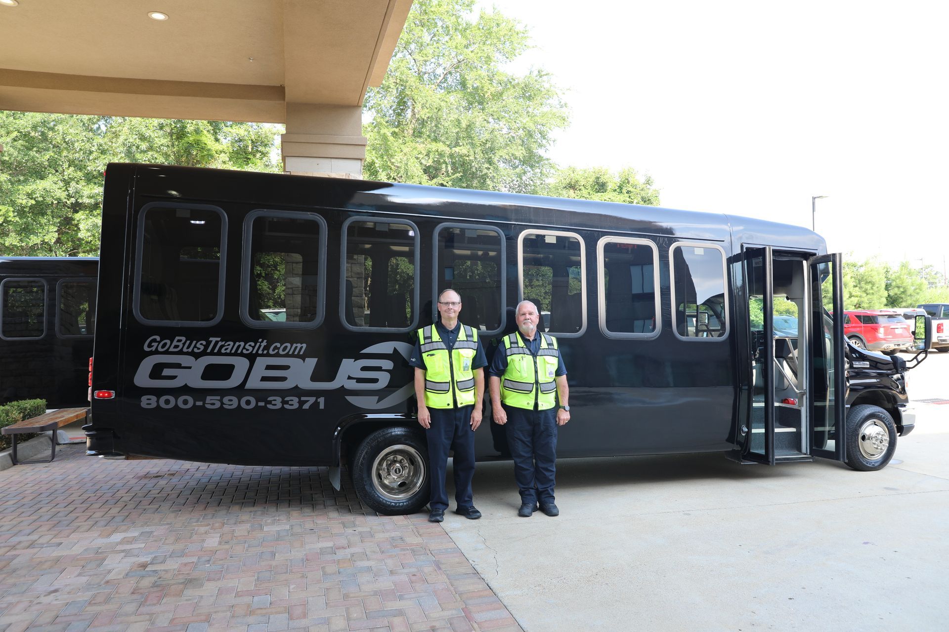 Two men are standing in front of a gobus bus.