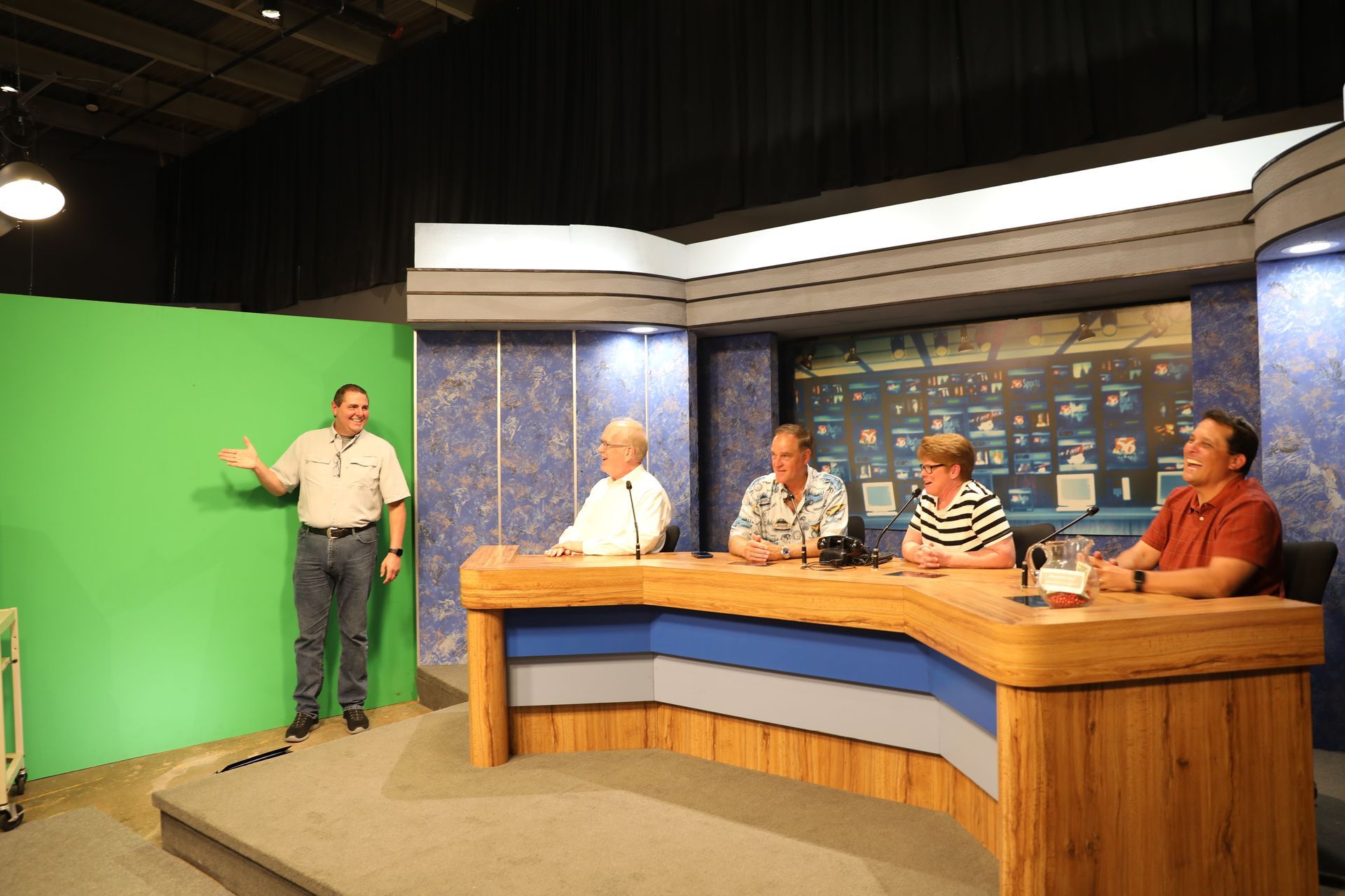 A group of people sitting at a table in front of a green screen