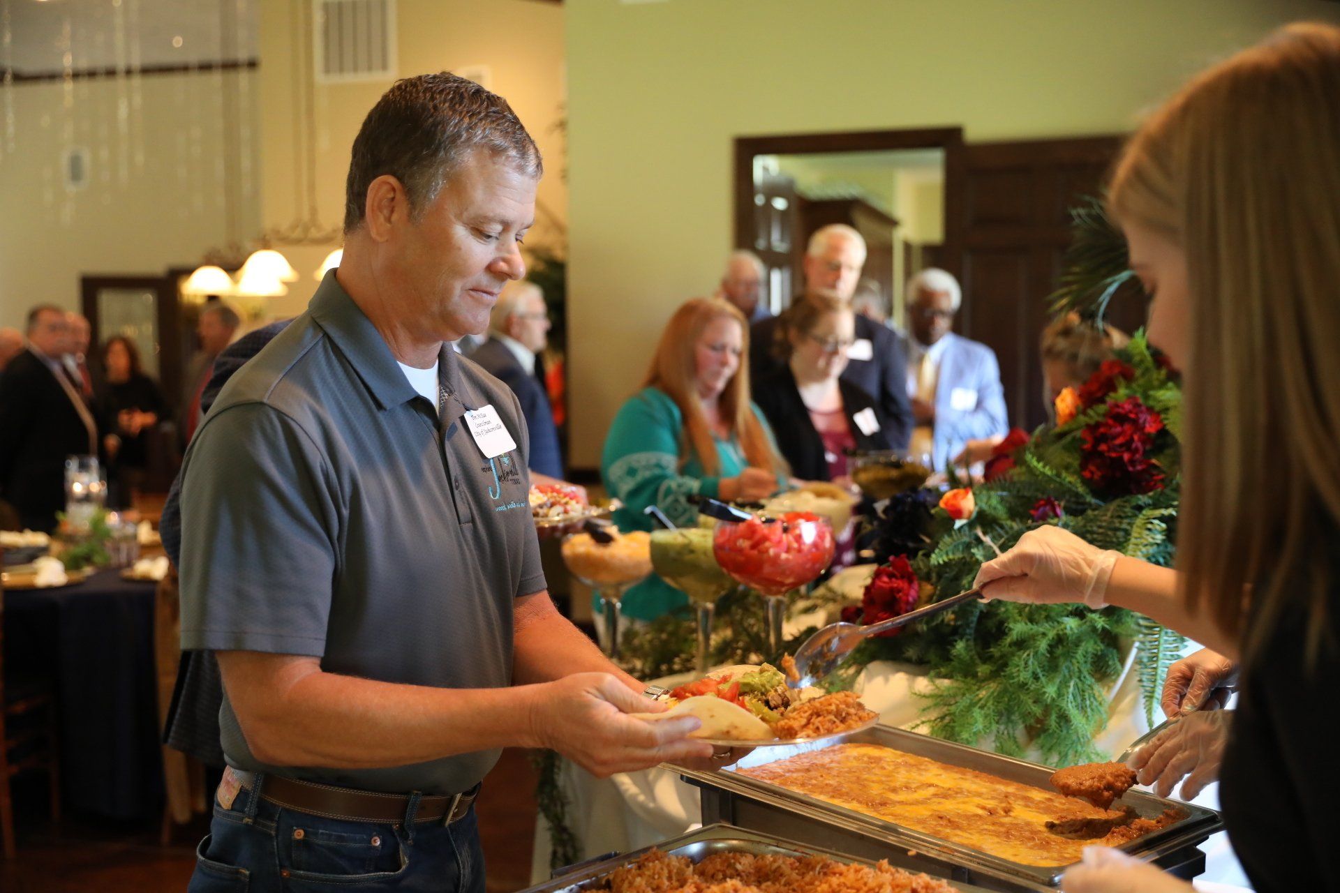 A man is serving food to a woman at a buffet table.