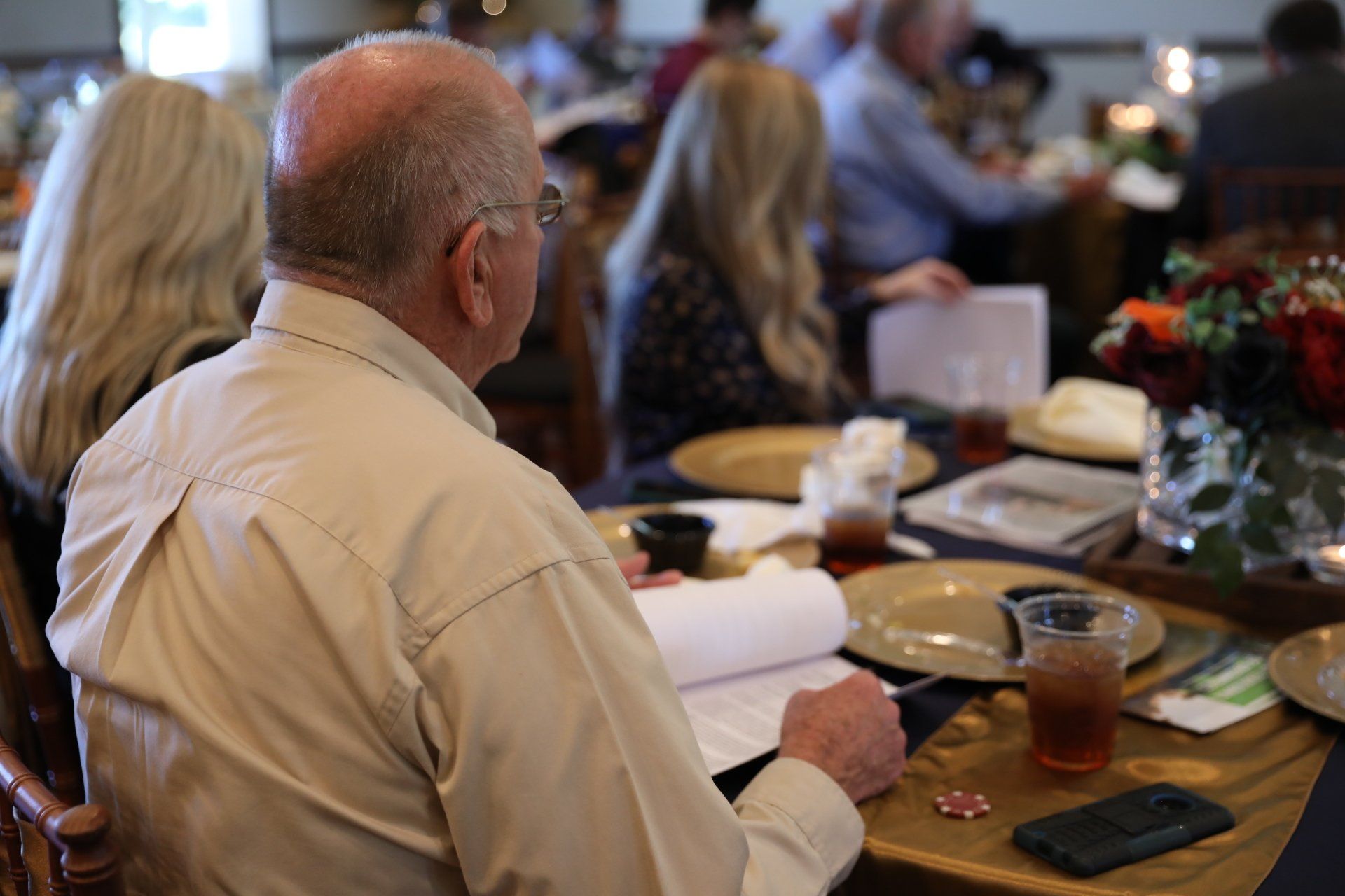 A man is sitting at a table looking at a piece of paper.