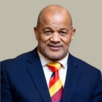 Smiling bald man in a navy suit with a colorful striped tie against a plain background
