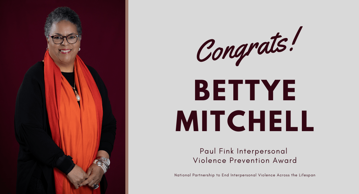 A woman in an orange scarf is standing next to a congratulations card for bettye mitchell.
