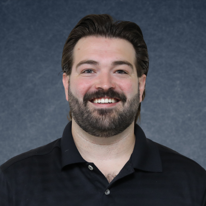 A man with a beard is smiling and wearing a black shirt