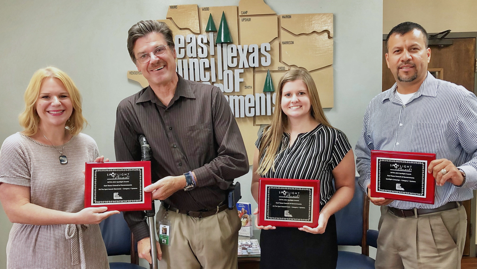 A group of people holding plaques in front of a gas texas sign