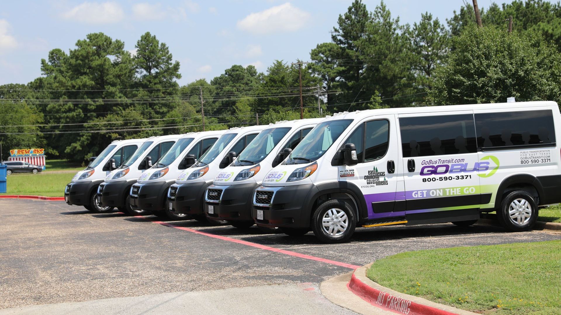 A row of vans are parked in a parking lot.