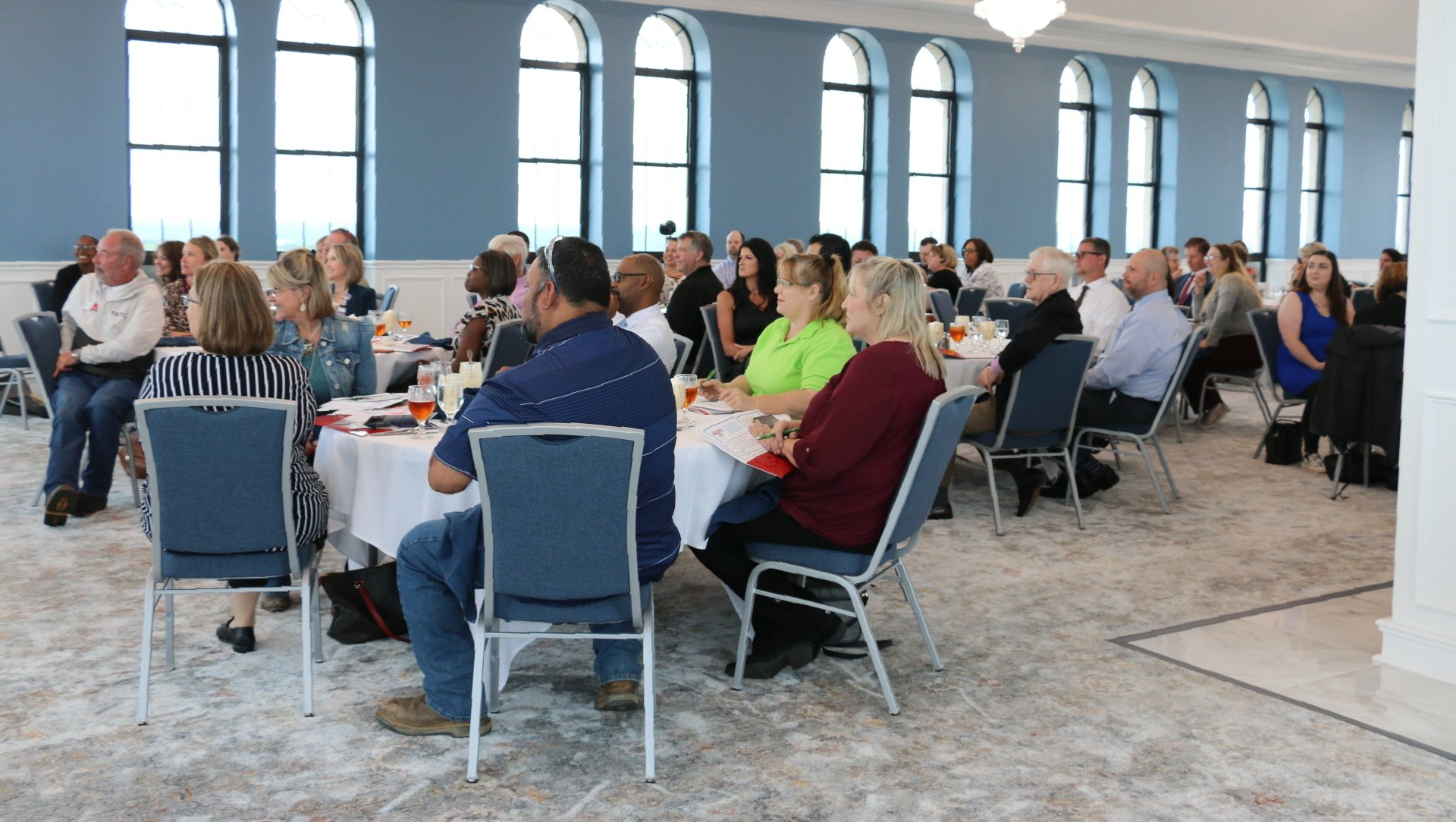 A large group of people are sitting at tables in a large room.