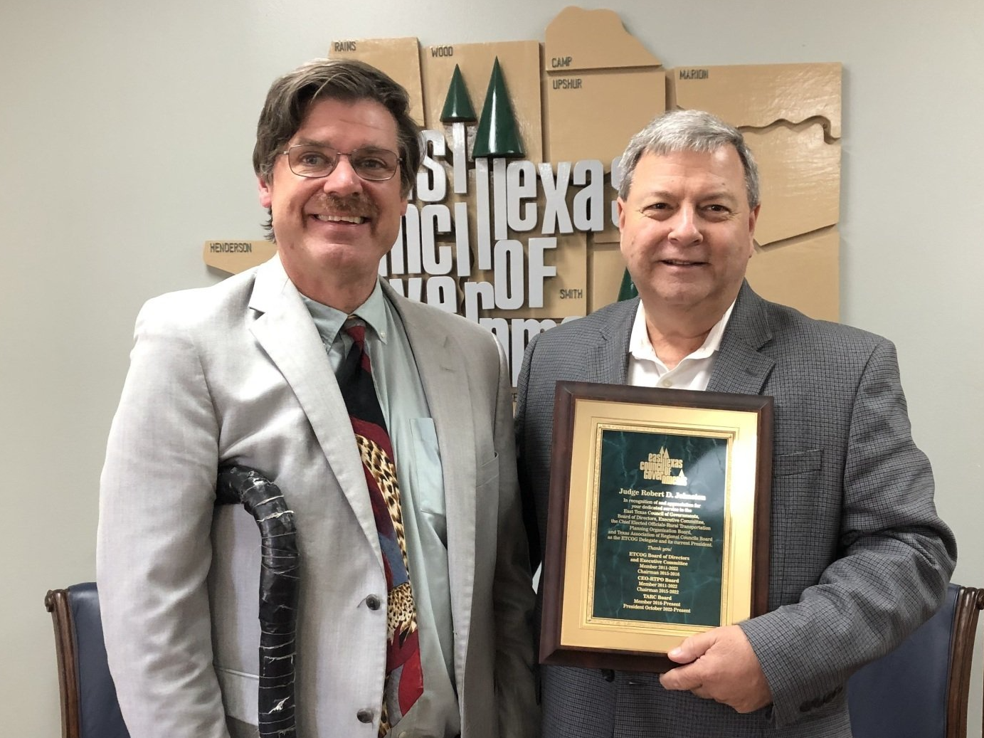 Two men are standing next to each other holding a plaque