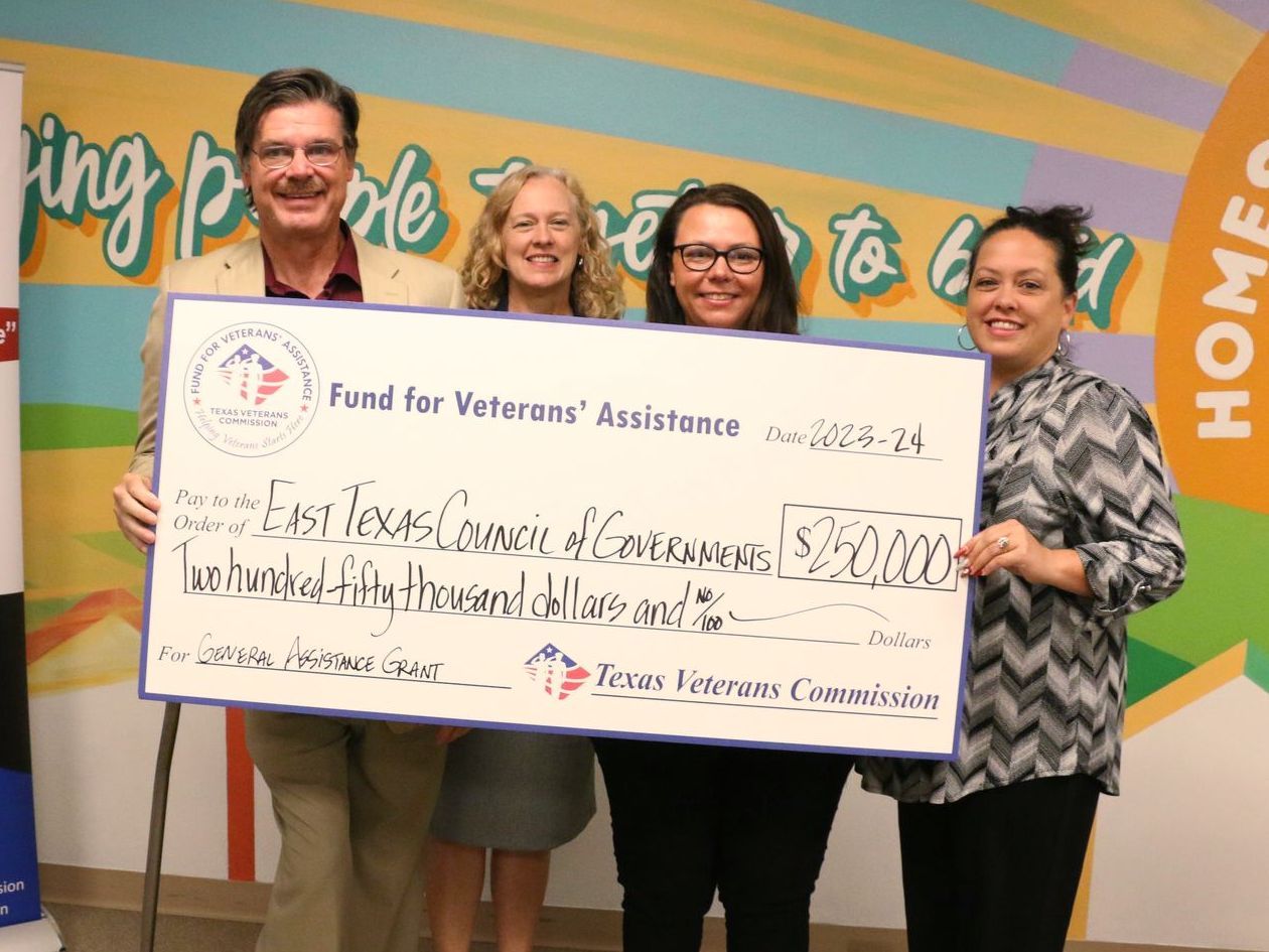 A group of people holding a large check that says find for veterans assistance
