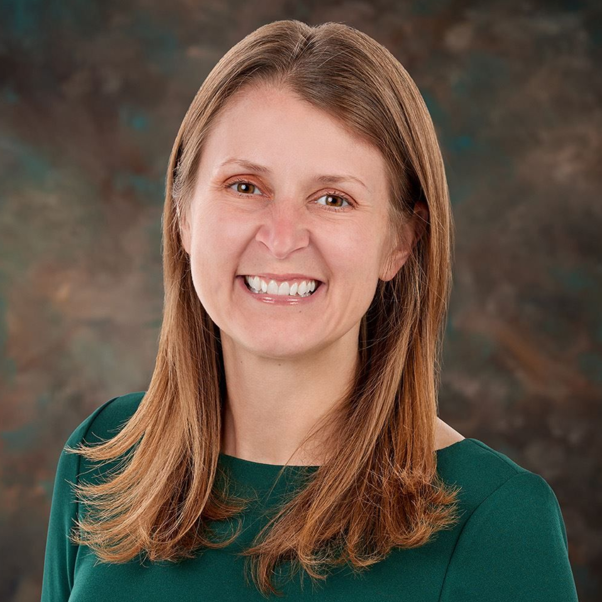 Smiling woman in a green top against a studio backdrop