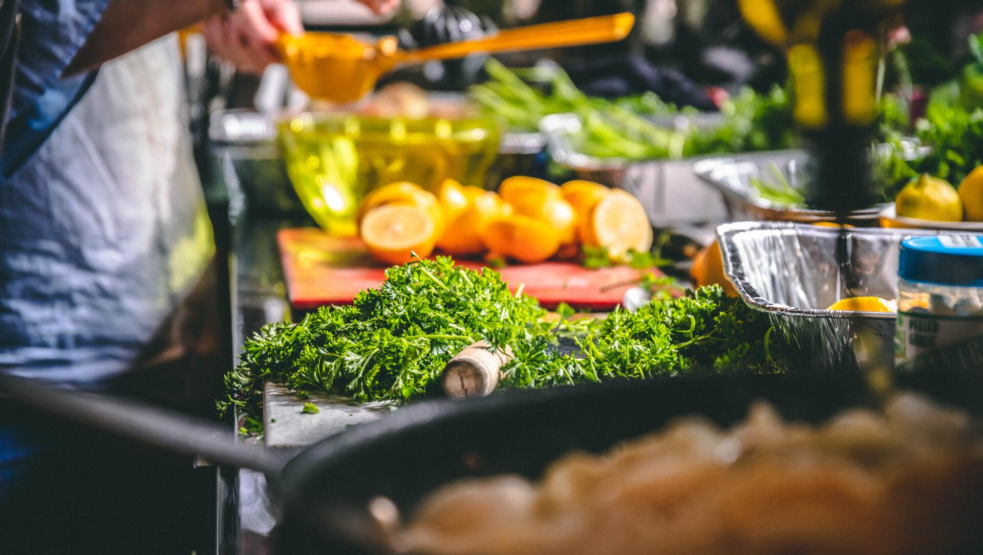A person is cooking food in a kitchen with vegetables on a table.