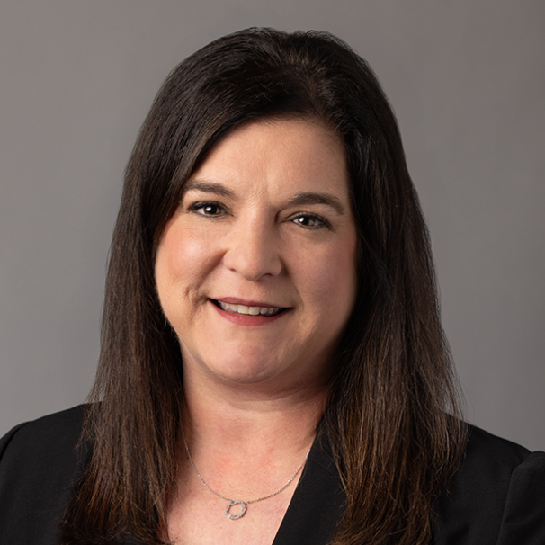 Portrait of a smiling woman in a black blazer against a gray background