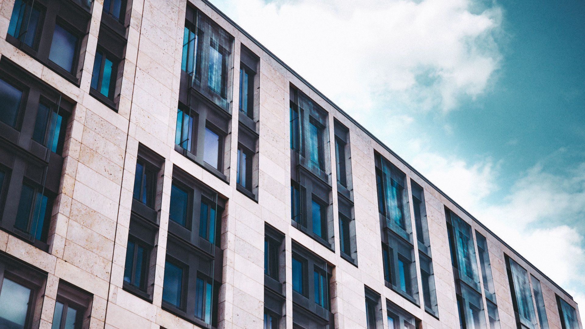 A large building with a lot of windows and a blue sky in the background.