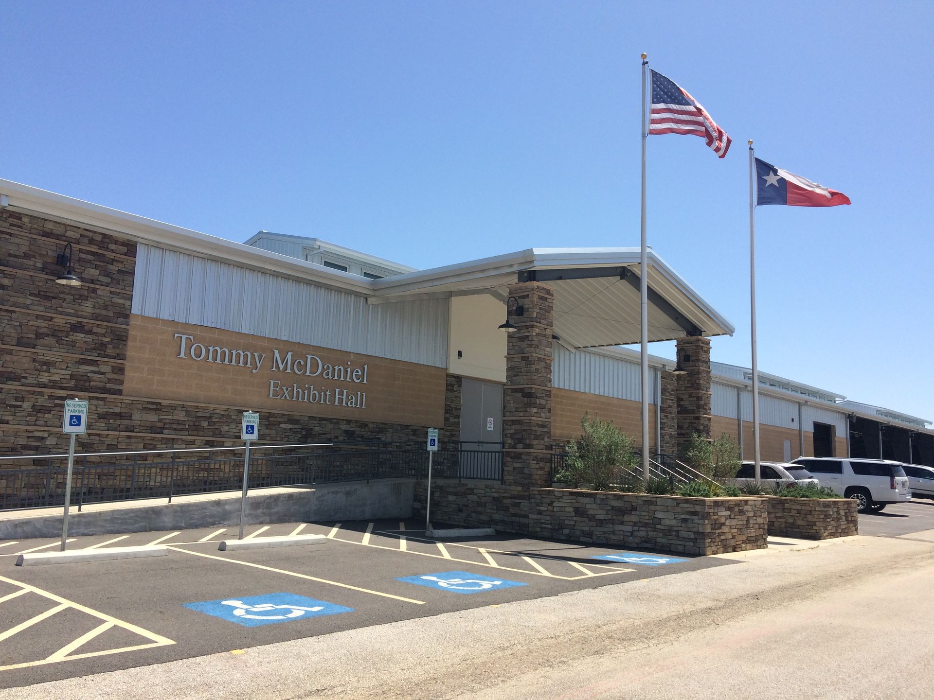 Tommy McDavid Park building exterior, Texas, accessible entrance, flags, parking, blue sky.