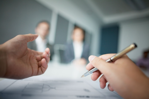 A client sits across from two employment lawyers in Toronto holding a pen.