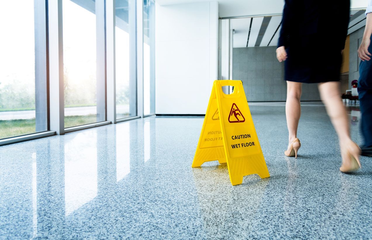  A yellow caution wet floor sign is displayed in an apartment building lobby to warn of slippery conditions, a safety measure to avoid a slip and fall injury lawsuit.