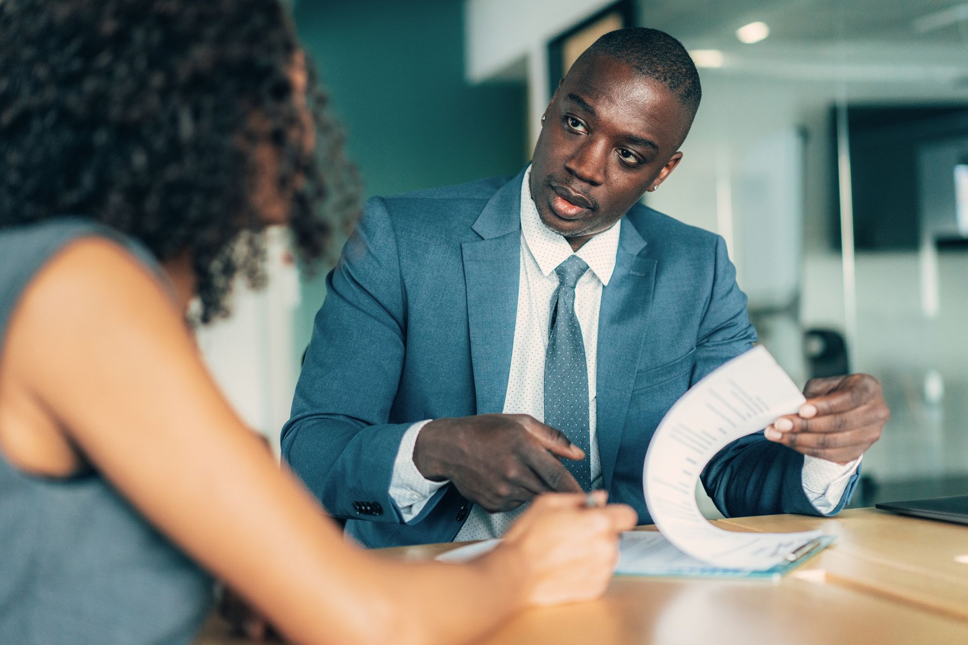 A professional disability lawyer in a suit discussing legal documents with a client at a desk. The client appears engaged and attentive.
